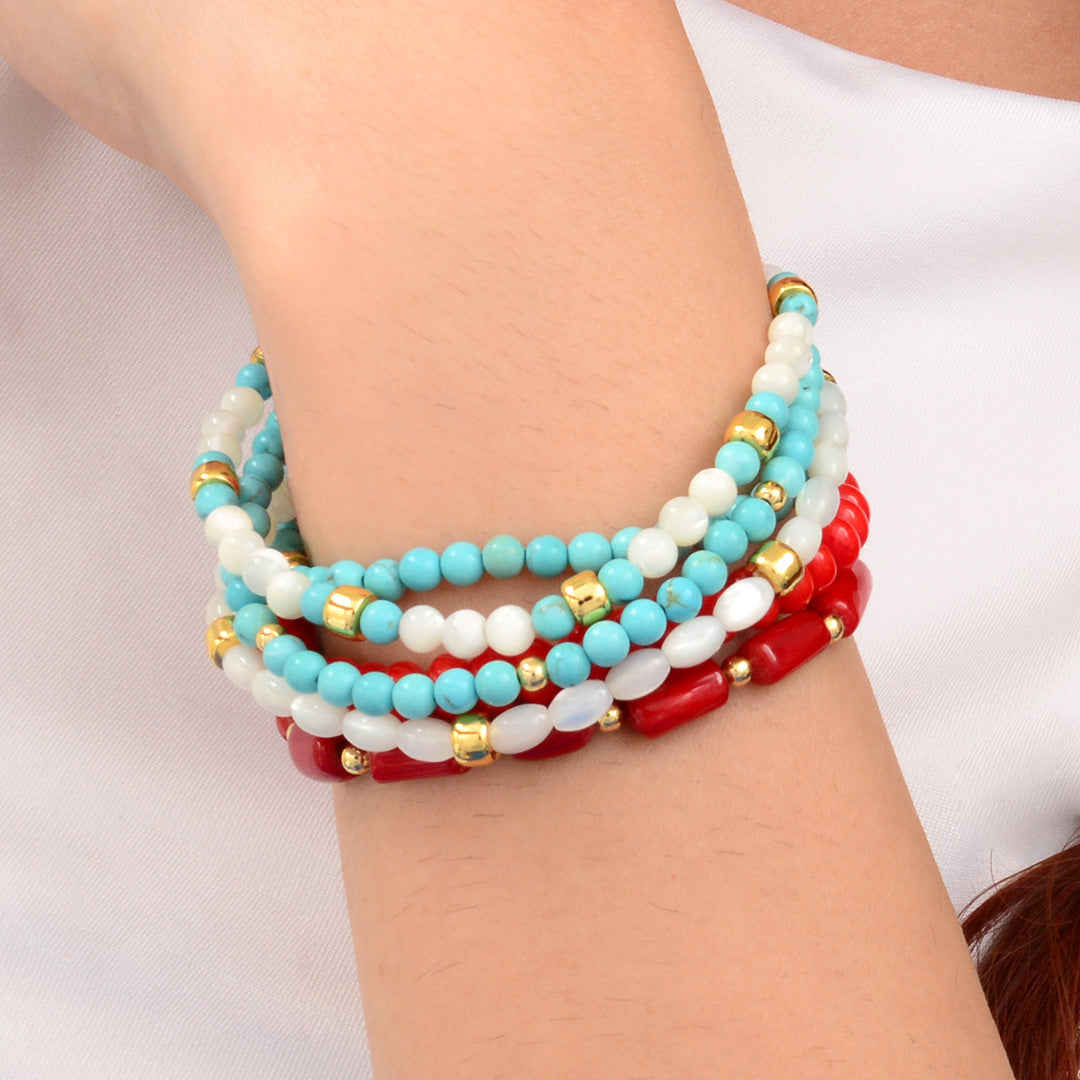 Stack of colorful beaded bracelets on a wrist against a neutral background