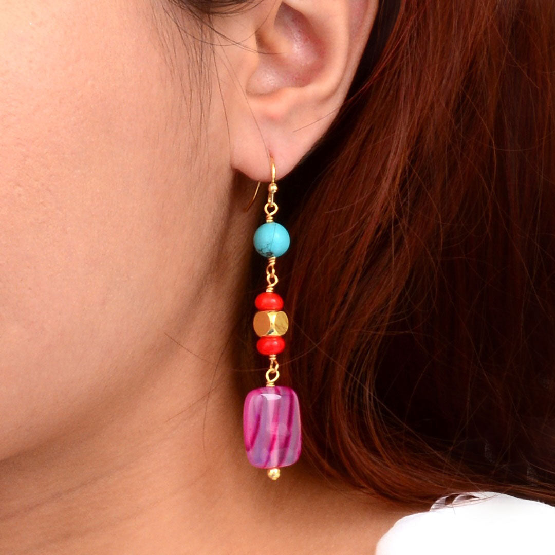 Close-up of colorful beaded earrings worn by a person with red hair.
