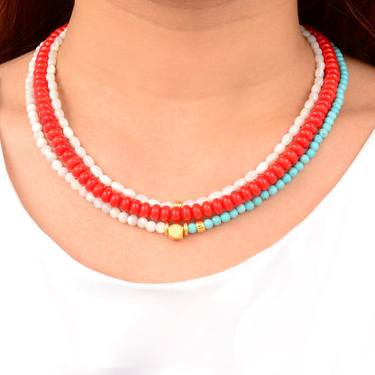 Necklace with red, white, and turquoise beads on a person wearing a white top.