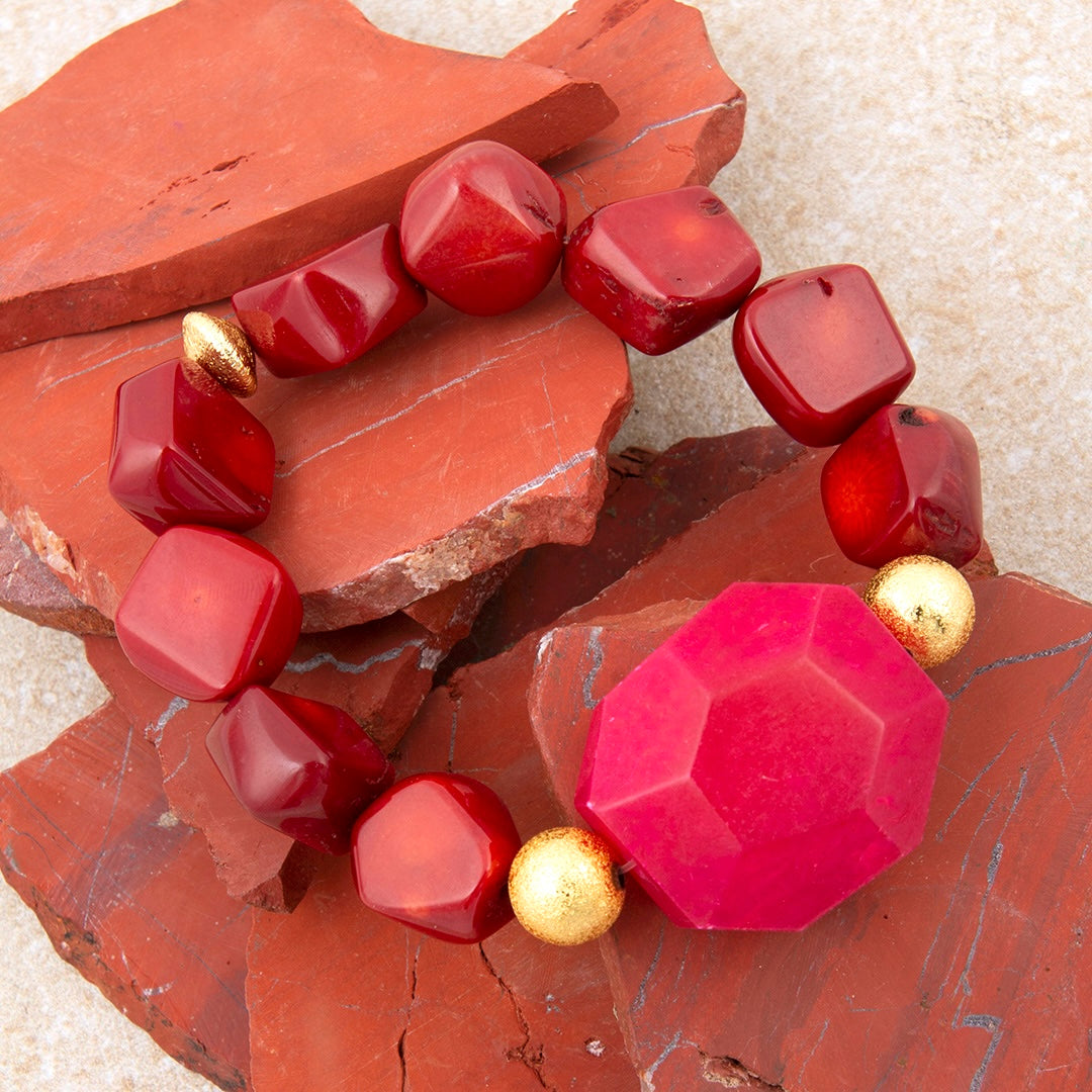 Bracelet with red and gold beads on a textured surface