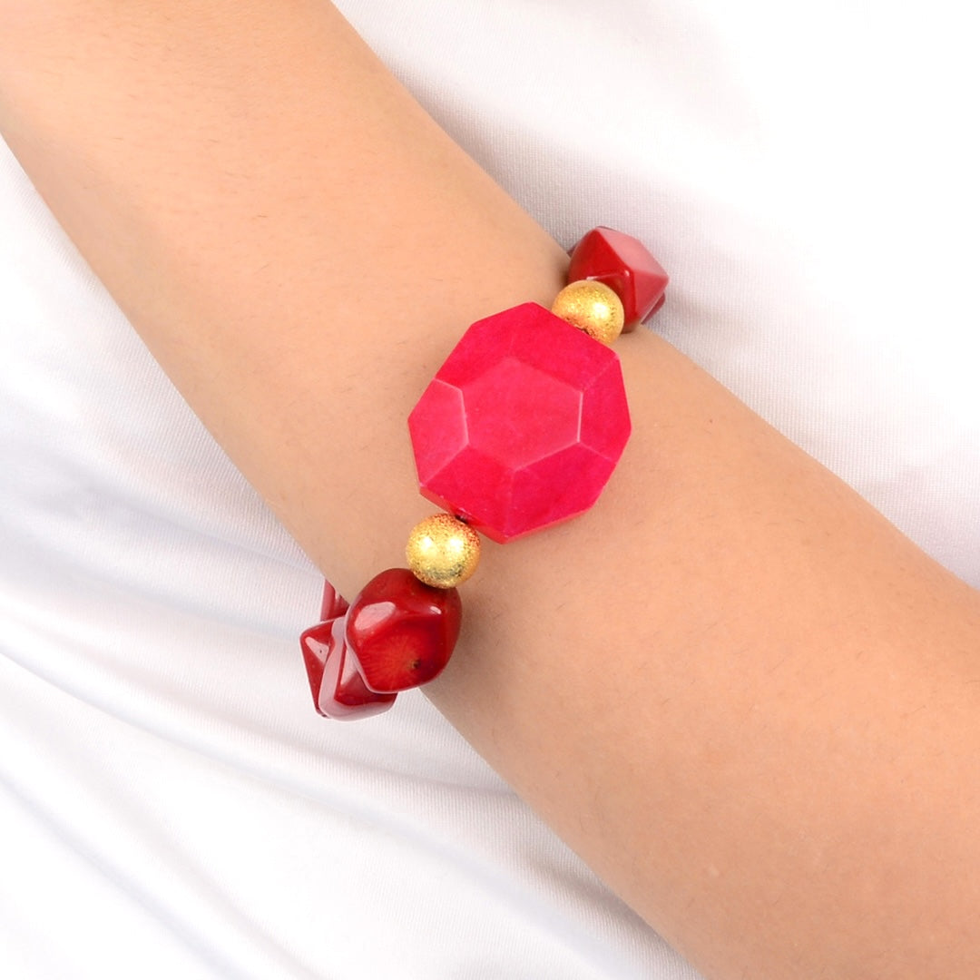 Bracelet with red and gold beads on a wrist against a white background