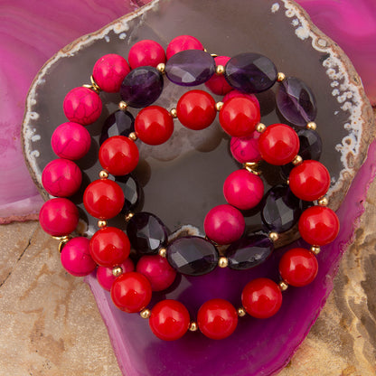 Stack of colorful beaded bracelets on a decorative stone surface