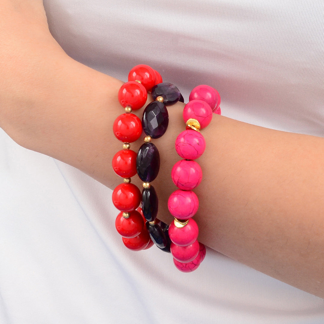 Two beaded bracelets, one red and one pink, on a wrist against a white background.