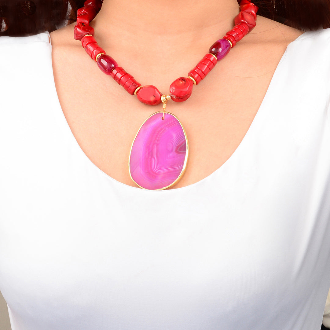Necklace with red beads and a pink pendant on a white background