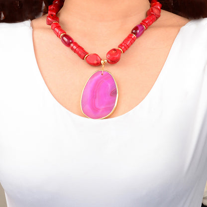 Necklace with red beads and a pink pendant on a white background