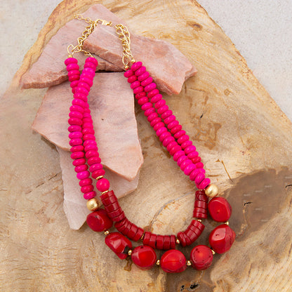 Necklace with pink and red beads on a stone surface