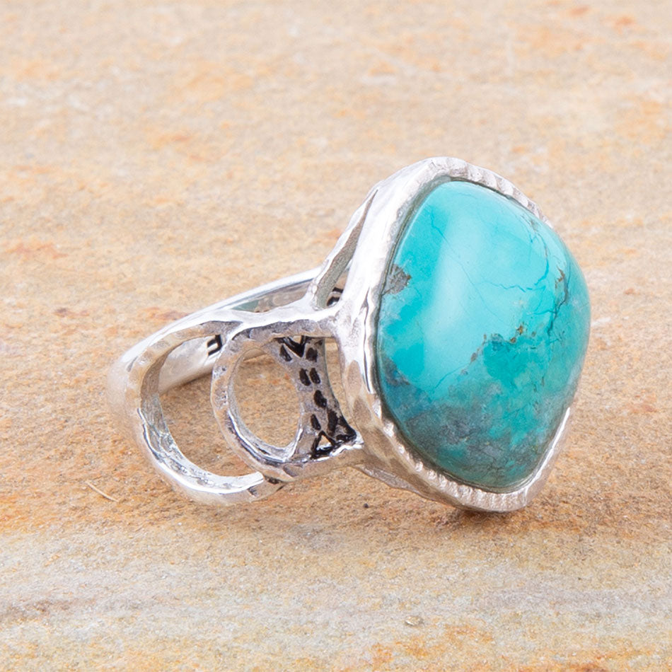 Turquoise ring with silver band on a beige stone background