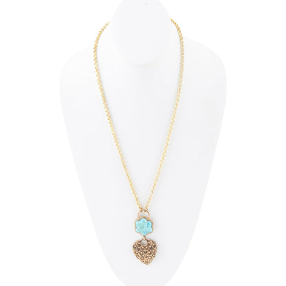 A gold chain necklace displayed on a white mannequin bust, featuring a double-drop pendant with a light blue flower charm and a textured gold heart.