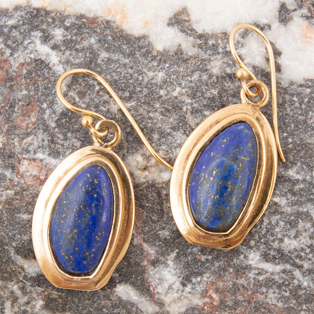 Gold-framed lapis lazuli earrings on a marble surface