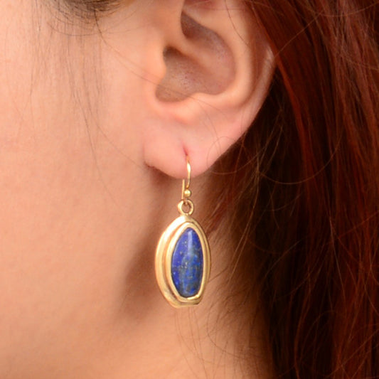 Gold earring with blue stone worn by a person
