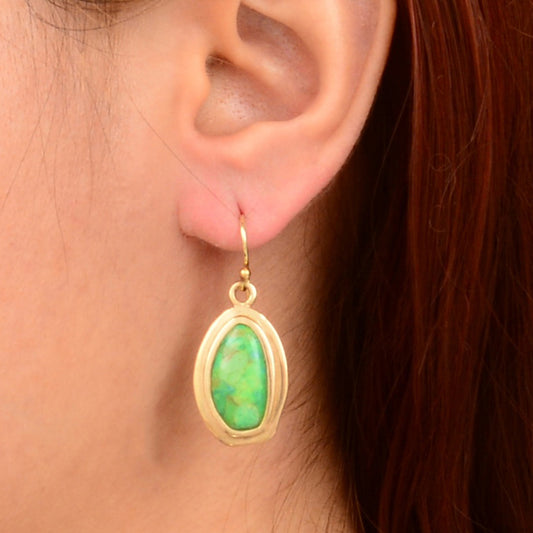 Gold earring with green gemstone worn by a person