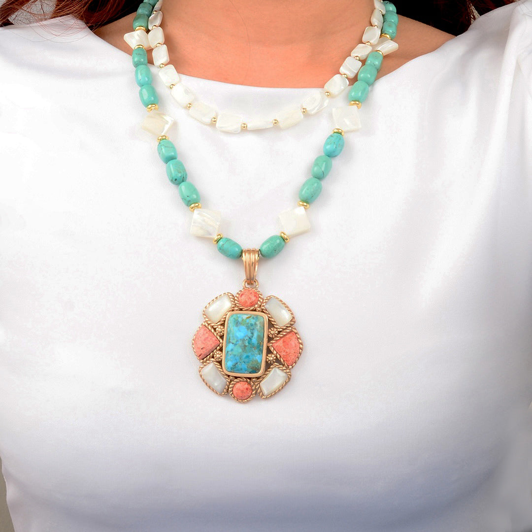 Necklace with turquoise and coral pendant on a white background