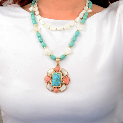 Necklace with turquoise and coral pendant on a white background