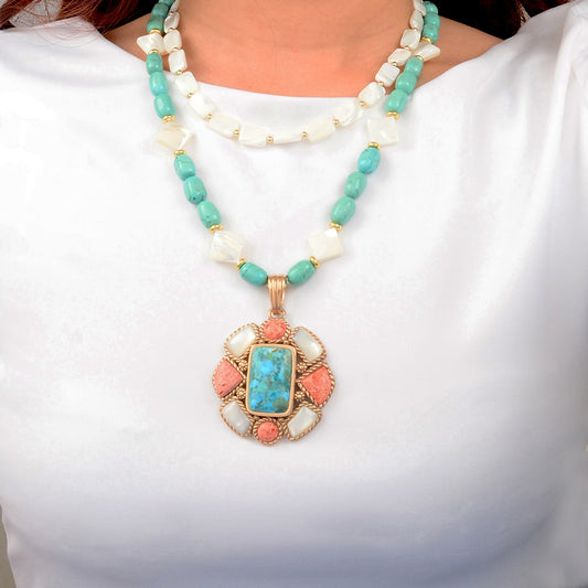 Necklace with turquoise and coral pendant on a white background