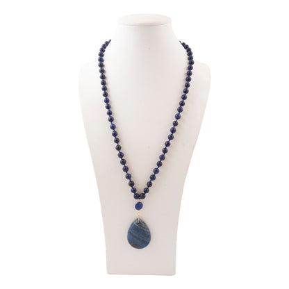 A beaded necklace with dark blue lapis lazuli-style round beads and a larger teardrop-shaped blue stone pendant, displayed on a white mannequin bust against a white background.