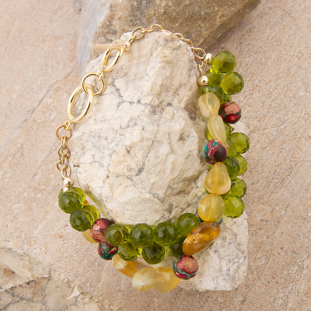 Beaded bracelet with green and yellow stones on a stone surface