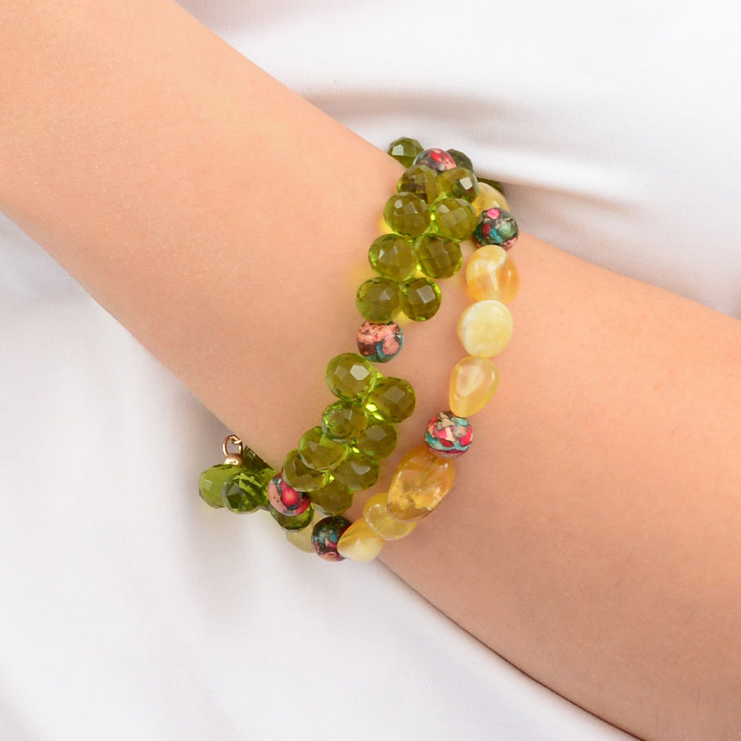 Green and yellow beaded bracelets on a wrist against a white background