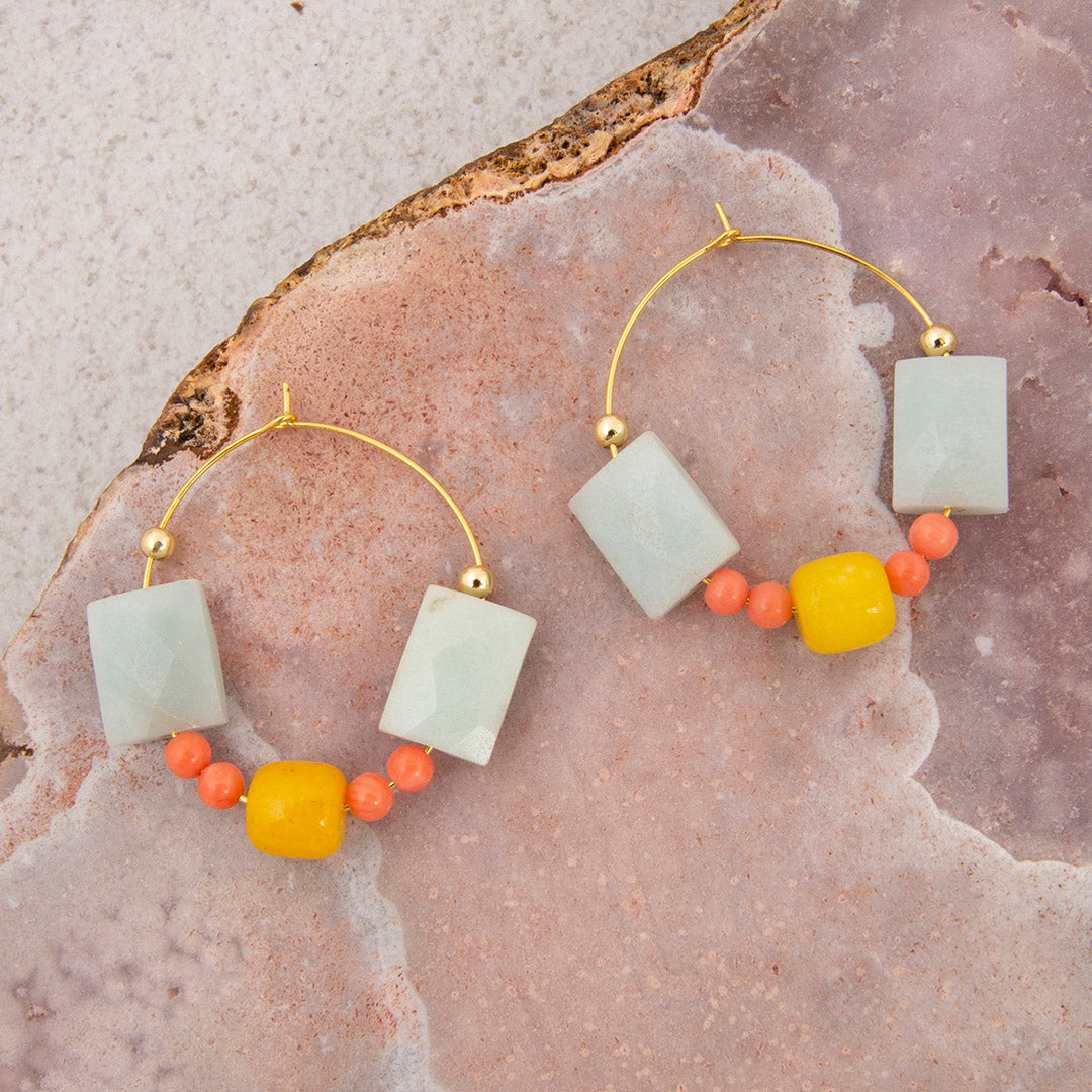Pair of hoop earrings with colorful beads on a stone surface