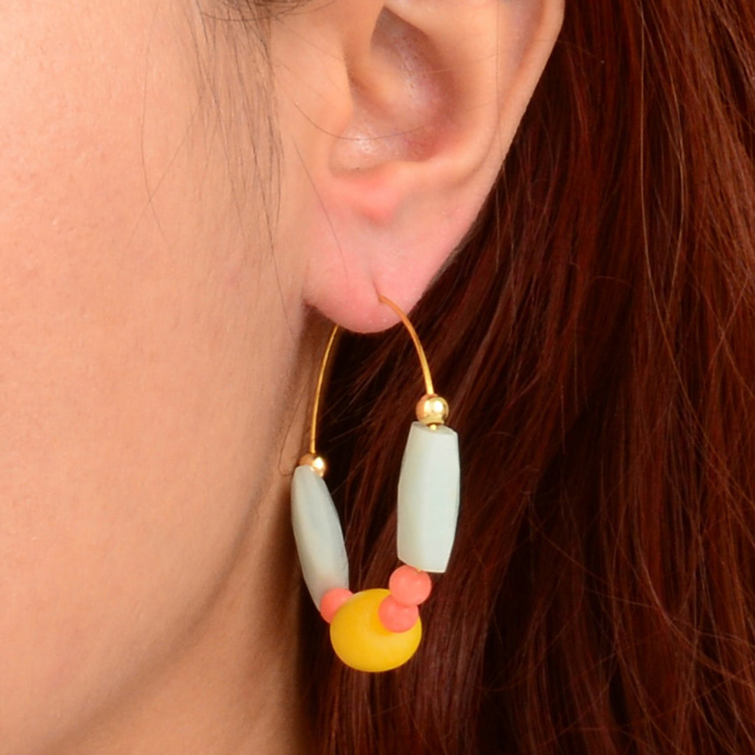 Close-up of an ear wearing a colorful beaded earring with a blurred background