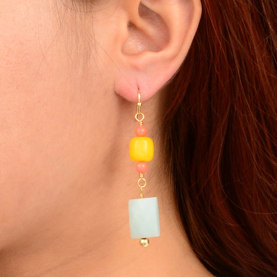 Close-up of an ear wearing a colorful beaded earring with a neutral background