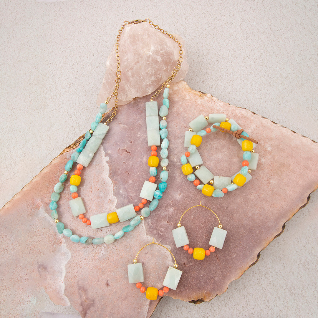 Jewelry set including necklace, bracelet, and earrings on a stone surface