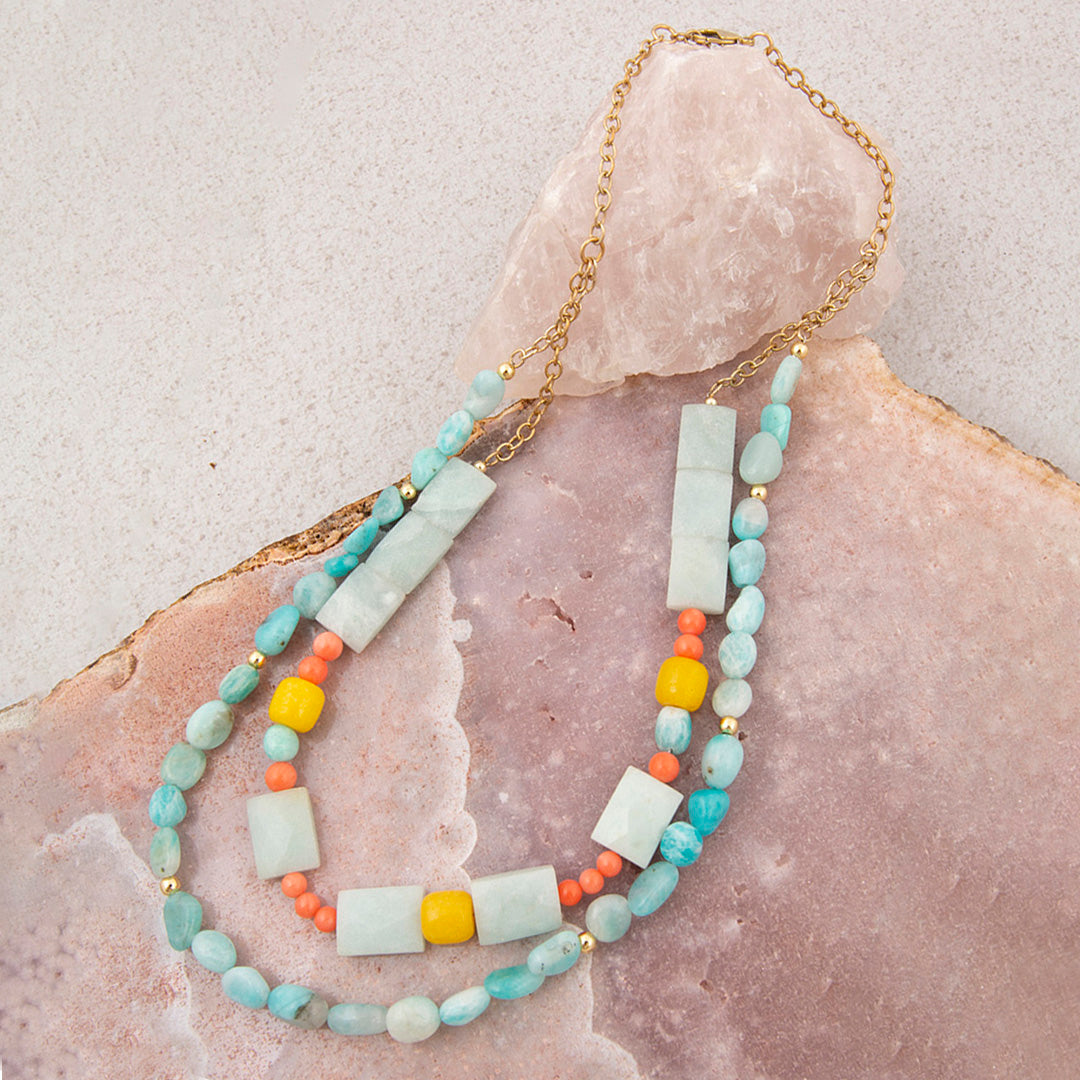 Multistrand necklace with turquoise, yellow, and coral beads on a stone surface