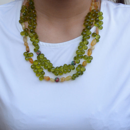 Necklace with green and multicolored beads on a white shirt