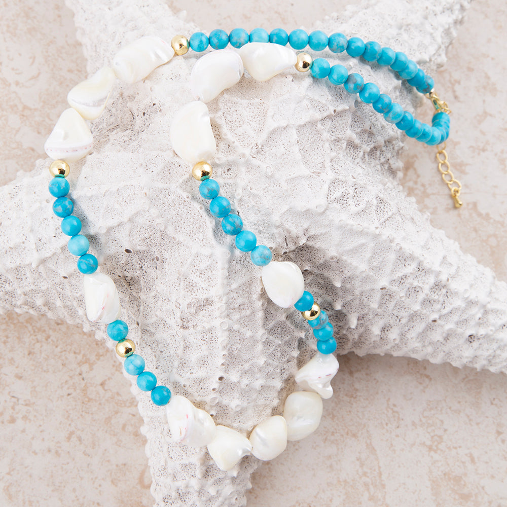 Two beaded bracelets displayed on a white starfish prop. One bracelet features light blue beads with small gold spacer beads, and the other features white baroque shell beads with light blue and gold accents.