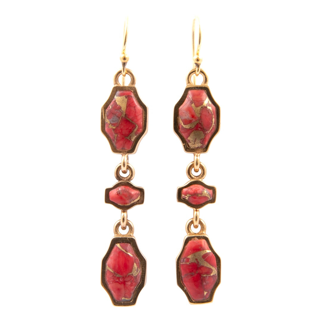 Pair of earrings with red stone and gold accents on a white background