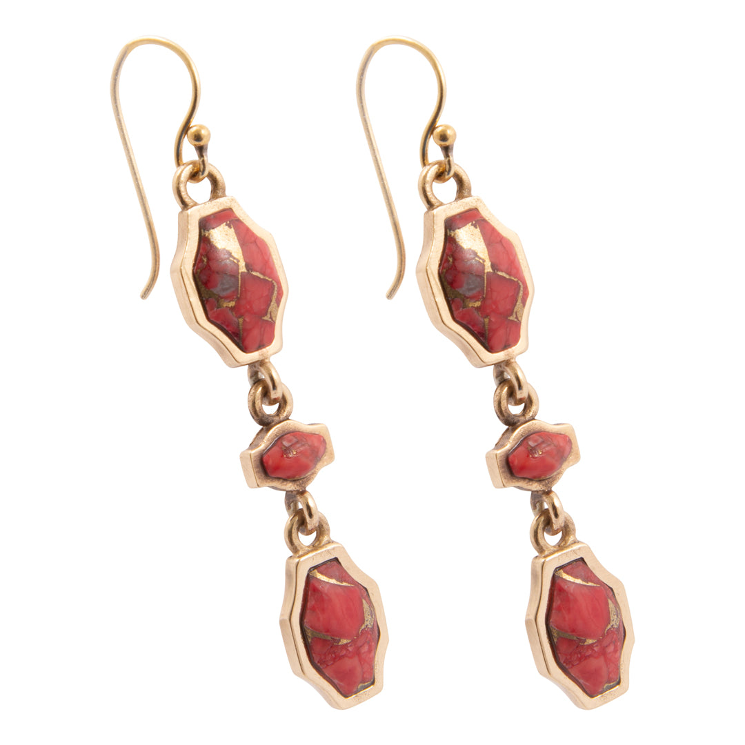 Gold earrings with red stone drops on a white background
