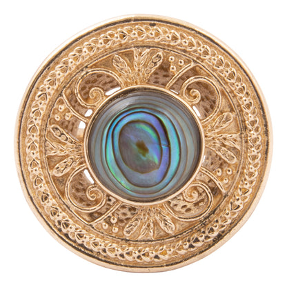 Decorative button with gold filigree and central abalone shell on a white background