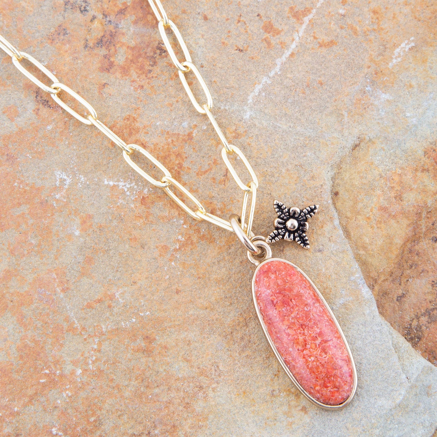Necklace with a pink pendant and star-shaped charm on a stone surface