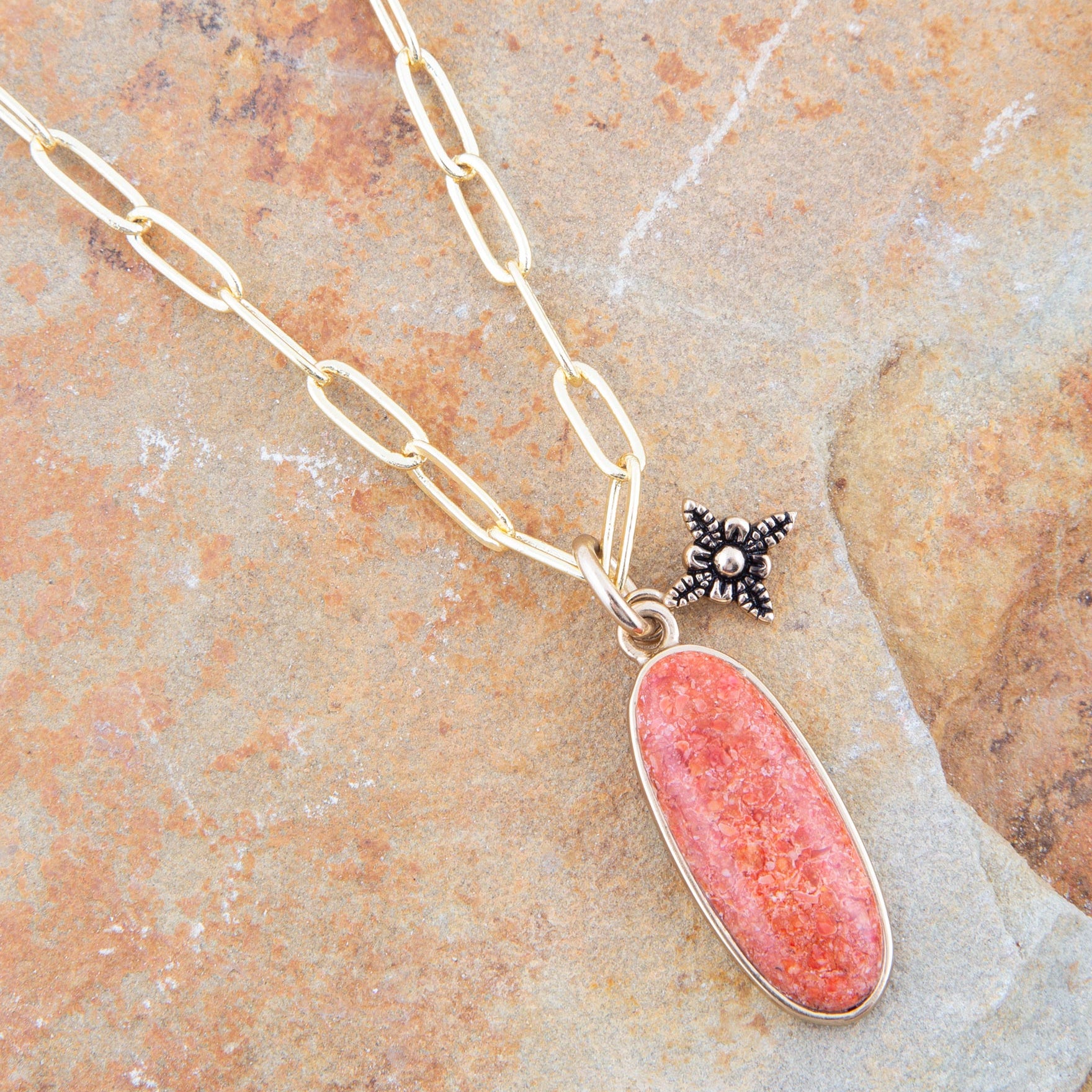 Necklace with a pink pendant and star-shaped charm on a stone surface
