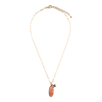 A delicate gold chain necklace featuring an oval copper pendant with a textured pattern and a small gold bird charm, displayed against a solid white background.