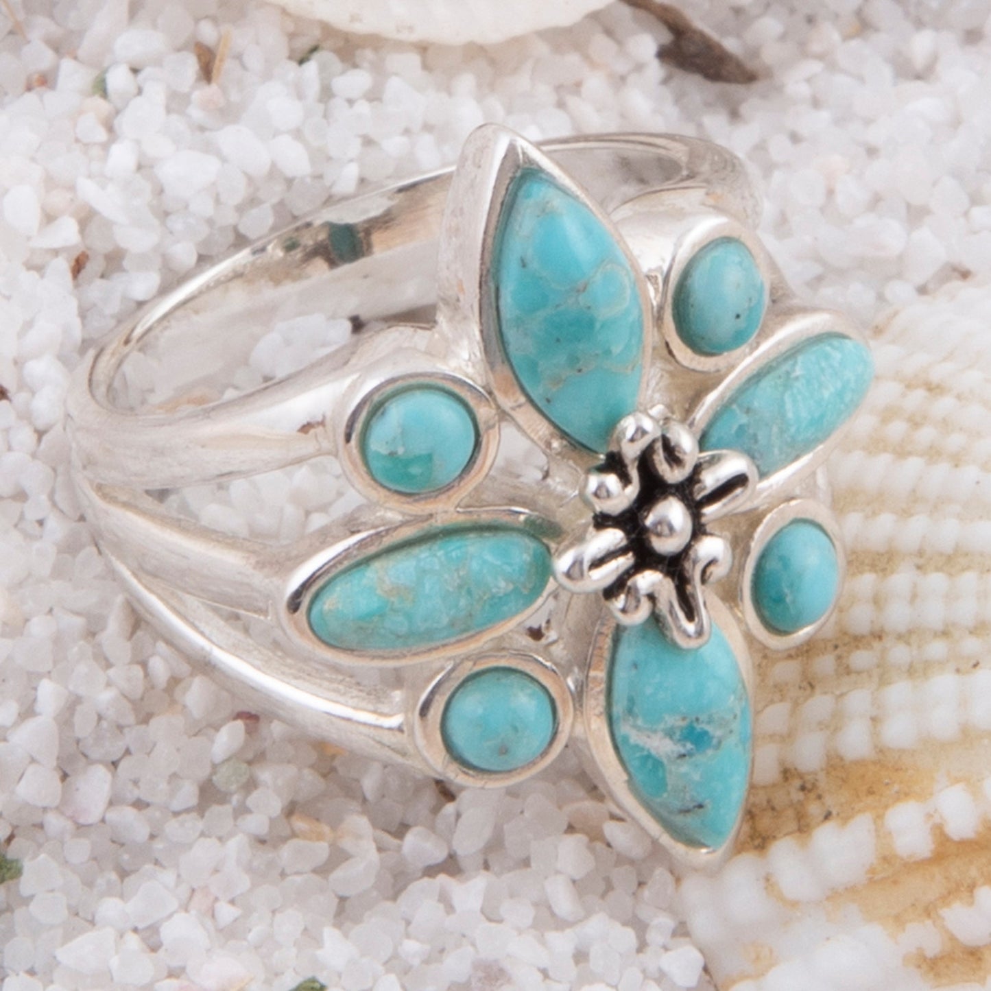 Silver ring with turquoise stones on a sandy background