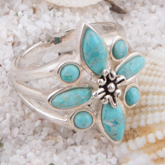 Silver ring with turquoise stones on a sandy background