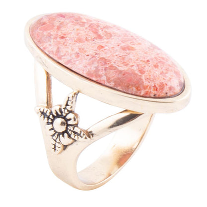 Ring with pink stone and sun design on a white background
