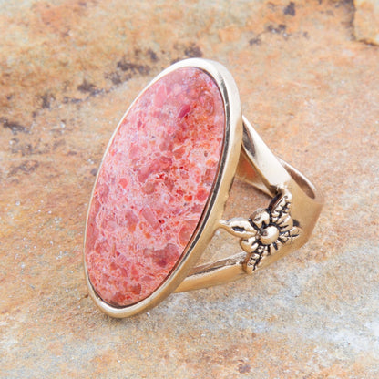 Ring with pink stone and gold band on a stone surface