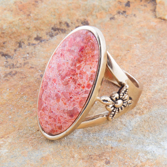 Ring with pink stone and gold band on a stone surface