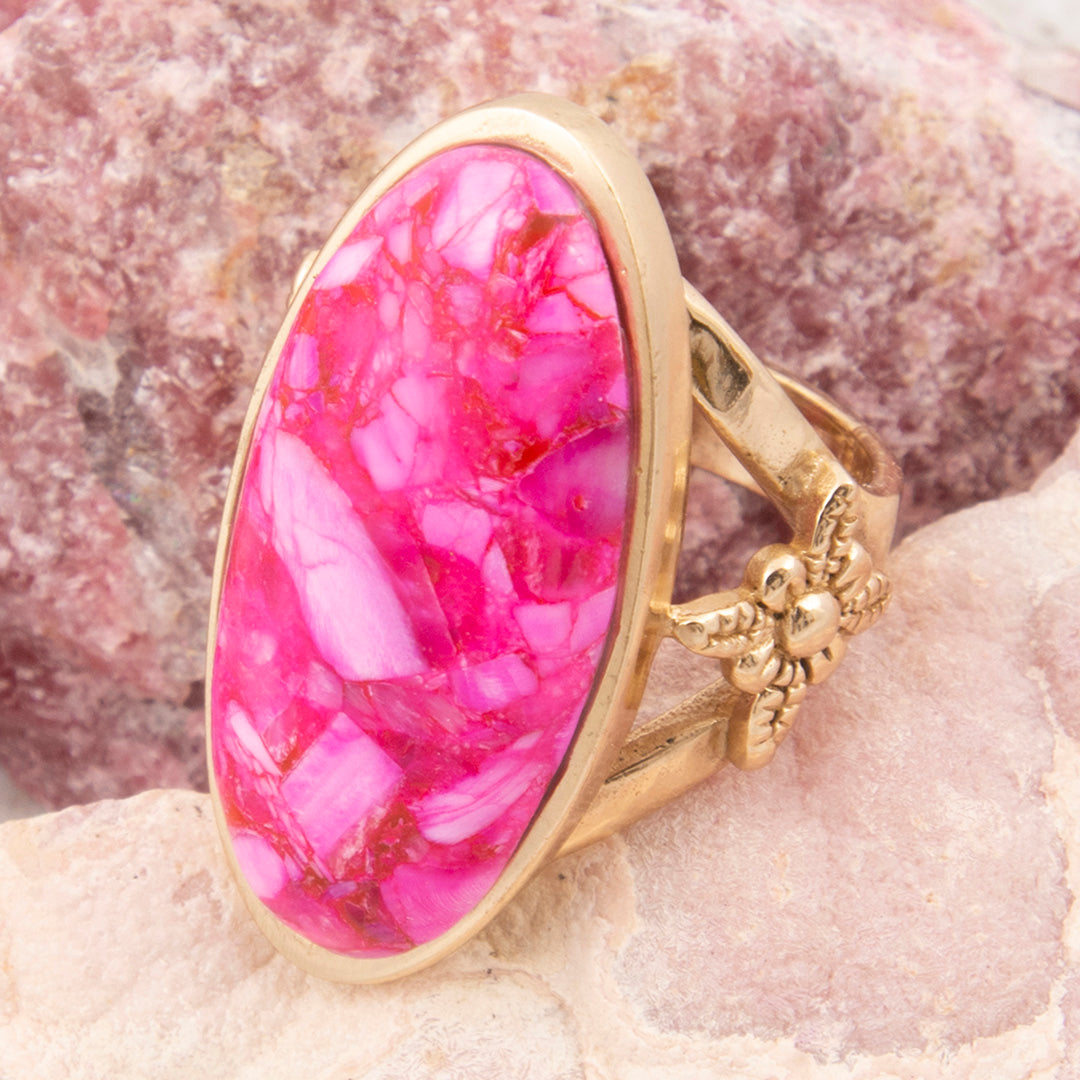 Gold ring with a pink stone on a textured surface