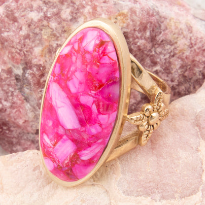 Gold ring with a pink stone on a textured surface