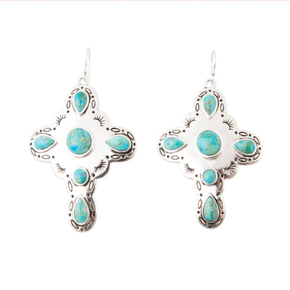 A pair of silver cross-shaped dangle earrings with turquoise stones, shown on a plain white background.