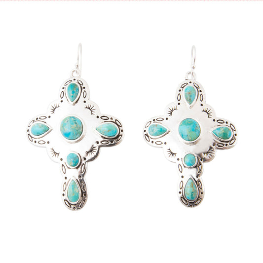 A pair of silver cross-shaped dangle earrings with turquoise stones, shown on a plain white background.