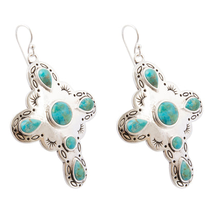 A pair of silver cross dangle earrings with turquoise stones, shown against a plain white background.