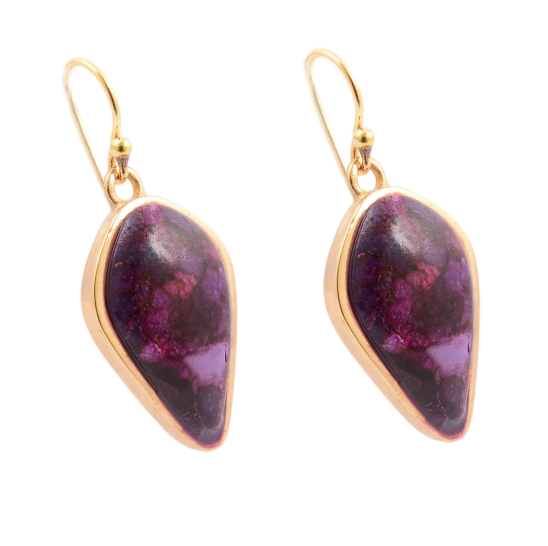 Pair of gold earrings with purple gemstones on a white background