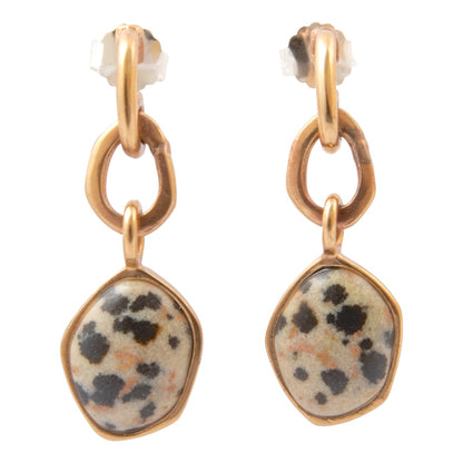 A pair of gold-tone dangle earrings with irregular organic-shaped cream and black spotted stone pendants, shown on a plain white background.
