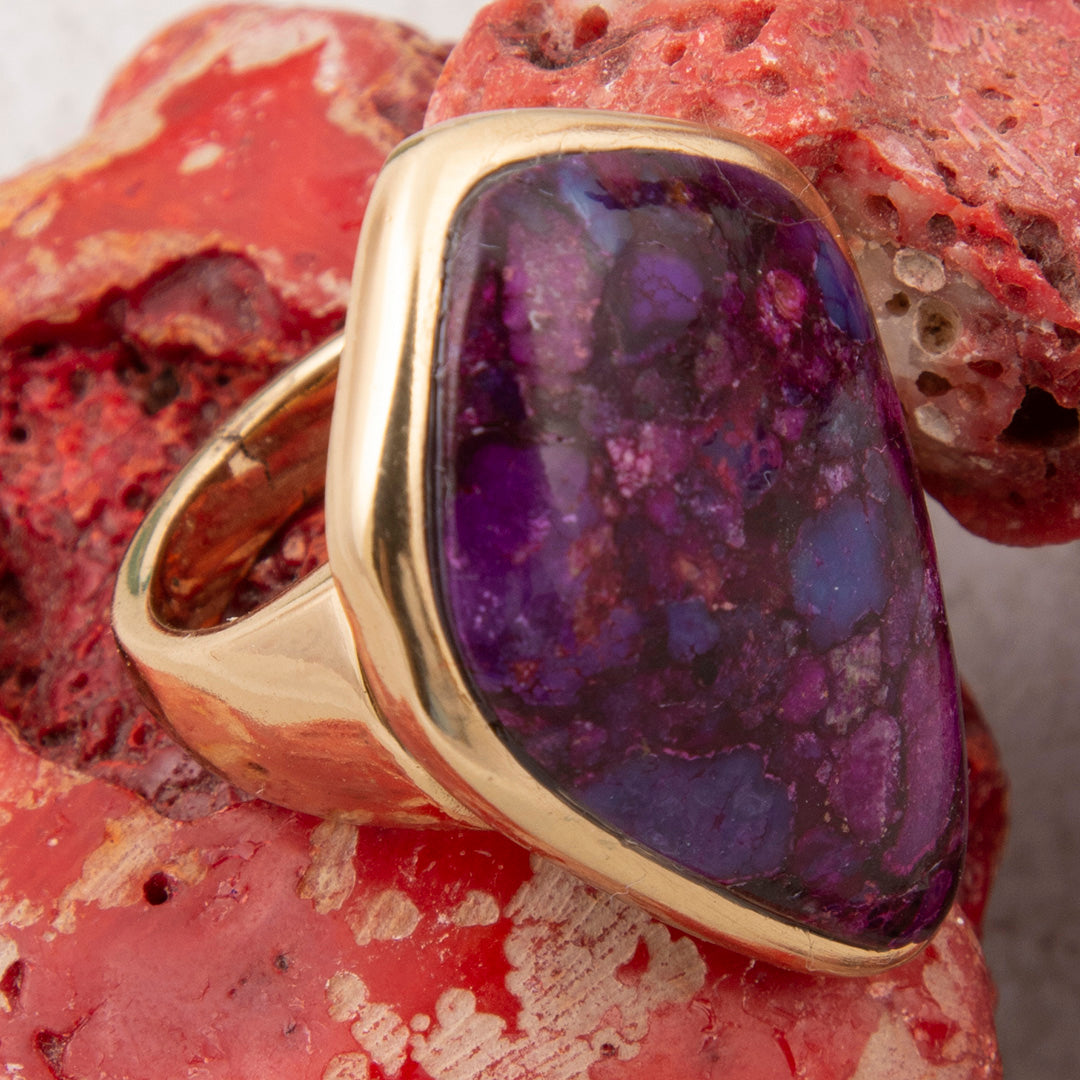 Gold ring with a purple gemstone on a red rock background