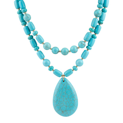 A multi-strand turquoise necklace featuring cylindrical, round, and teardrop-shaped beads with a natural stone crackle pattern, suspended on a white background.