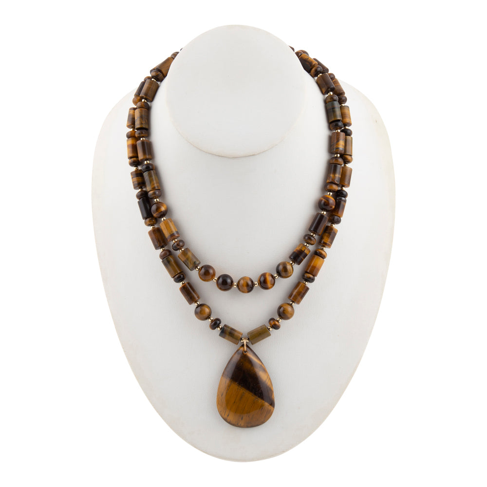 A double-strand necklace made of polished tiger's eye beads with a teardrop-shaped pendant, displayed on a white mannequin bust against a white background.