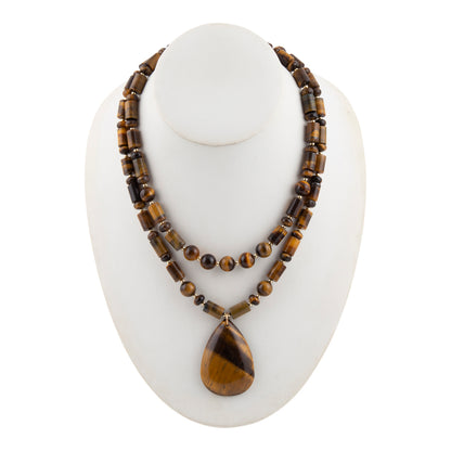 A double-strand necklace made of polished tiger's eye beads with a teardrop-shaped pendant, displayed on a white mannequin bust against a white background.